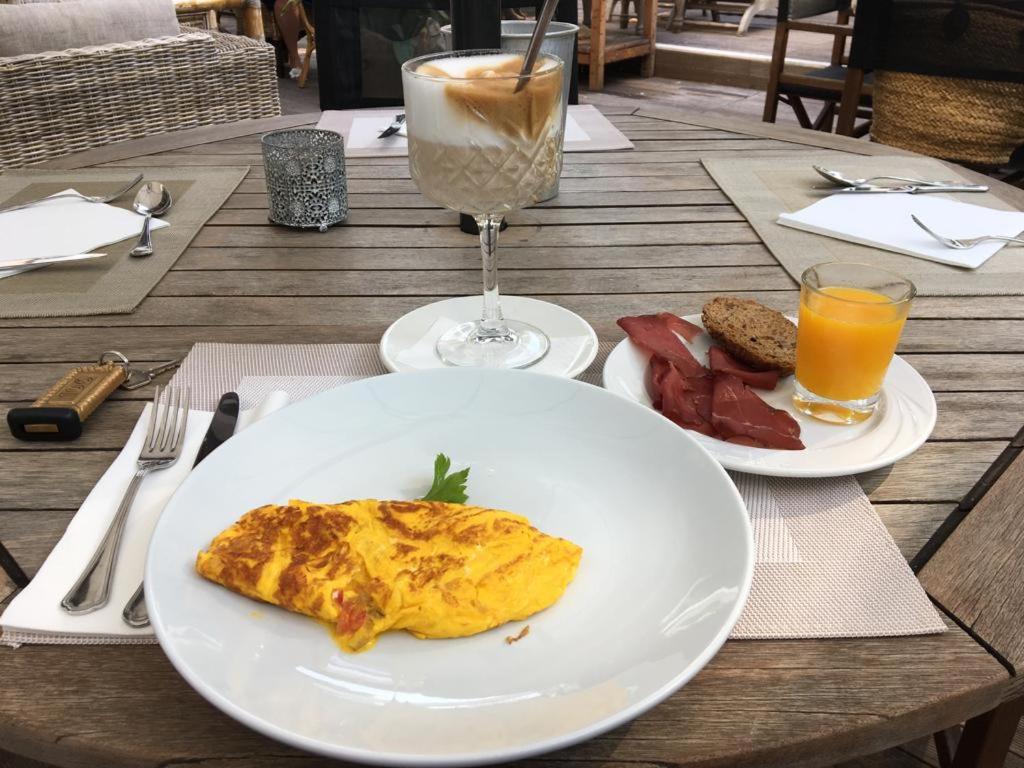une table avec deux assiettes de nourriture et un verre de jus d'orange dans l'établissement Hotel Saraceno Resort with Private Beach, à Milano Marittima