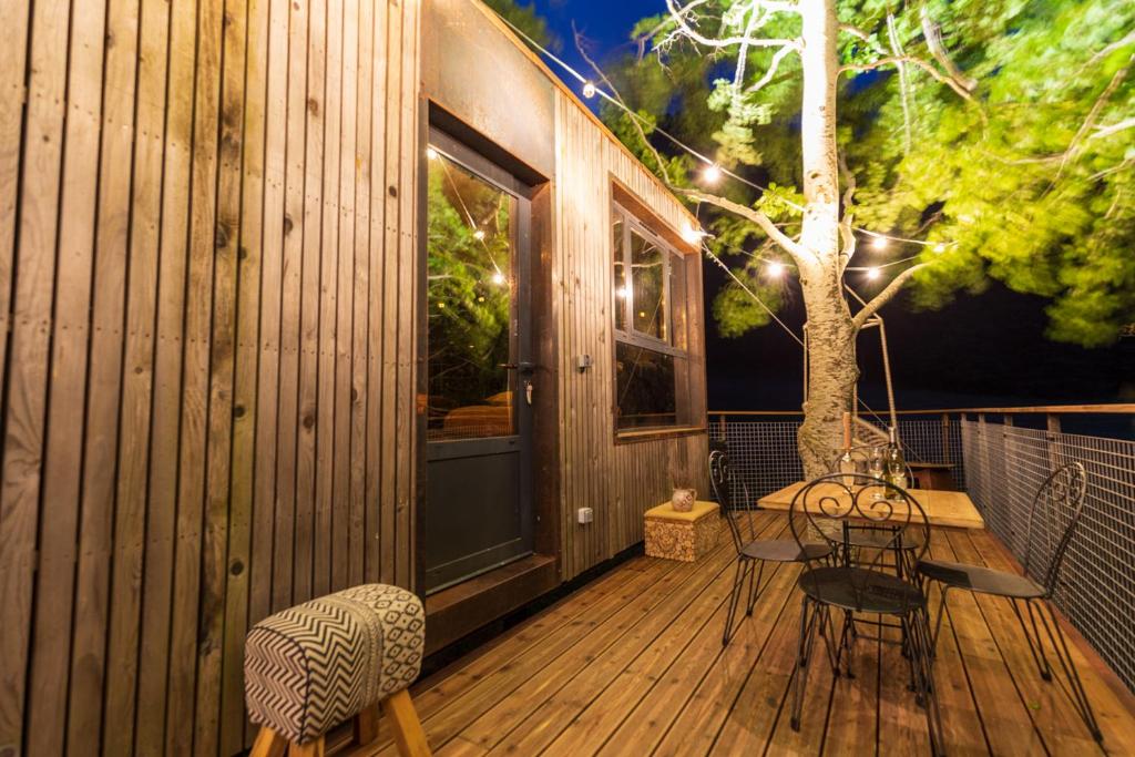 une terrasse en bois avec des chaises et un arbre. dans l'établissement Cabane perchée La Résilience sur le plateau du Vercors, à Autrans