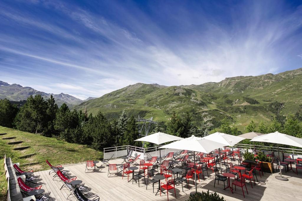 un groupe de tables et de chaises avec des montagnes en arrière-plan dans l'établissement Belambra Clubs Les Menuires - Neige Et Ciel, aux Menuires