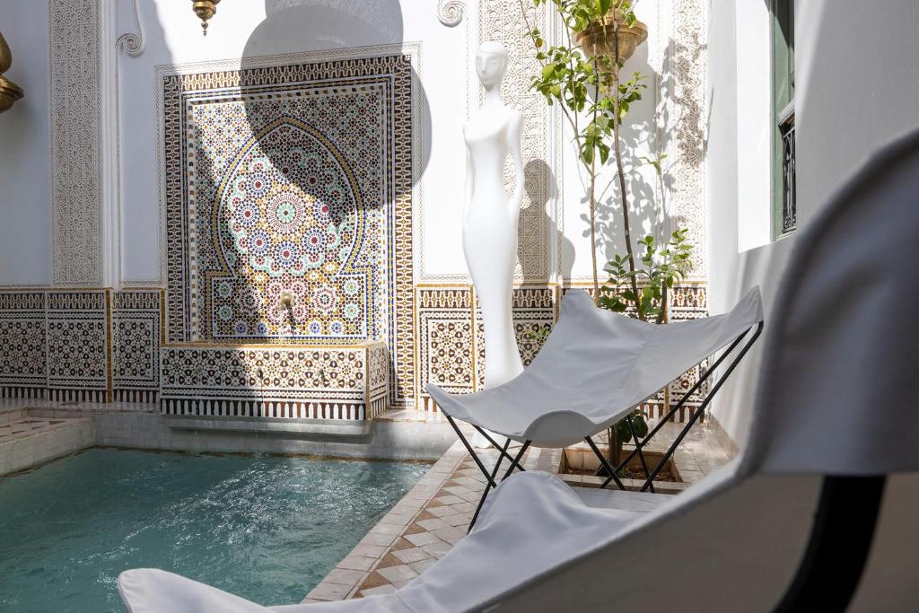 une piscine avec deux chaises et un mur en mosaïque dans l'établissement Riad LAZ Mimoun & Spa, à Marrakech