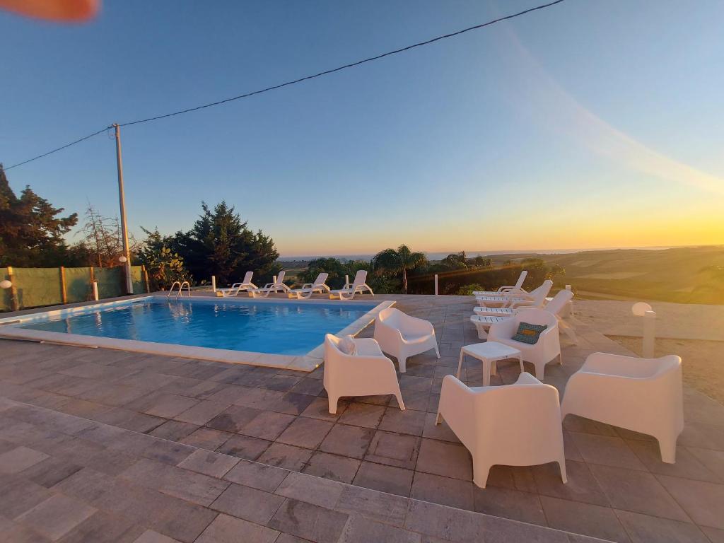 - un groupe de chaises blanches et une piscine dans l'établissement Villa Sara, à Sciacca