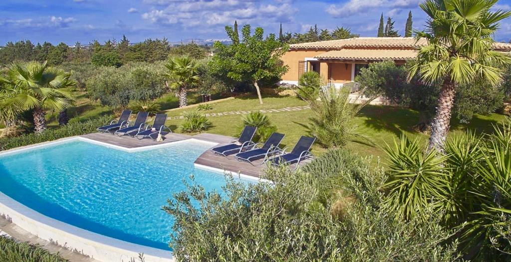 une piscine avec des chaises et une maison dans l'établissement Luxury Sicily Villas by Geocharme, à Castelvetrano