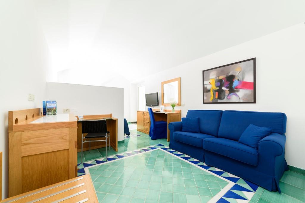 - un salon avec un canapé bleu et un bureau dans l'établissement Grand Hotel San Pietro, à Palinuro
