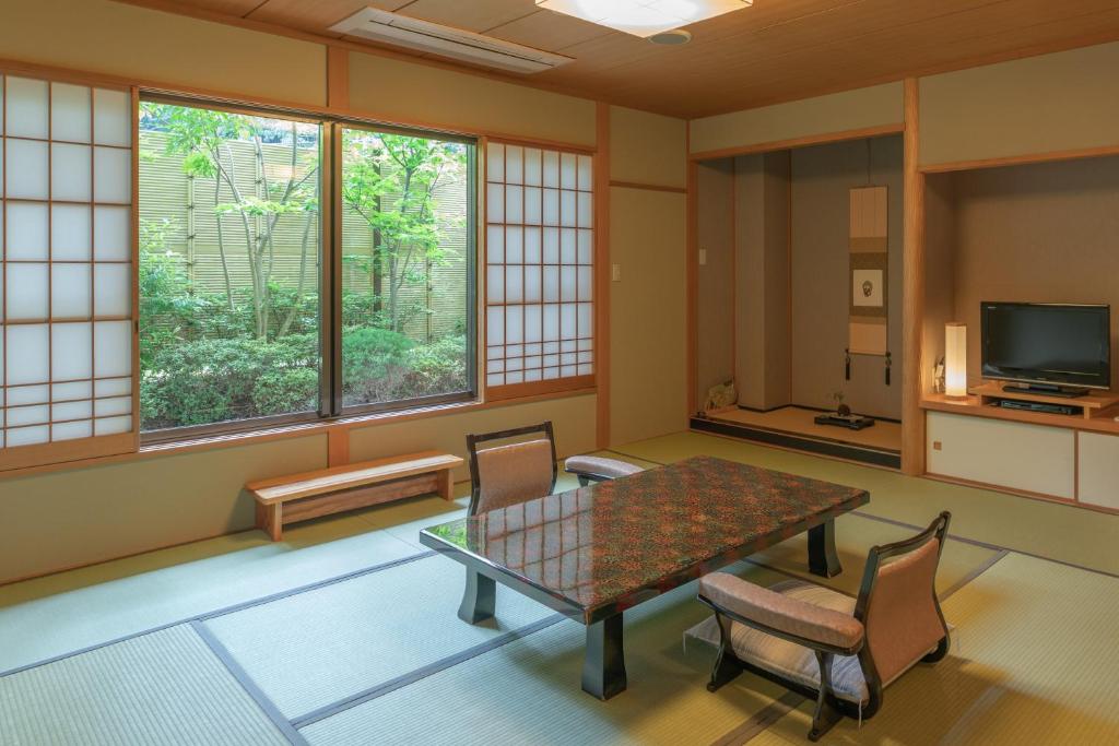 une pièce avec une table, des chaises et des fenêtres dans l'établissement Gyokusui -Adult Only-, à Higashiizu