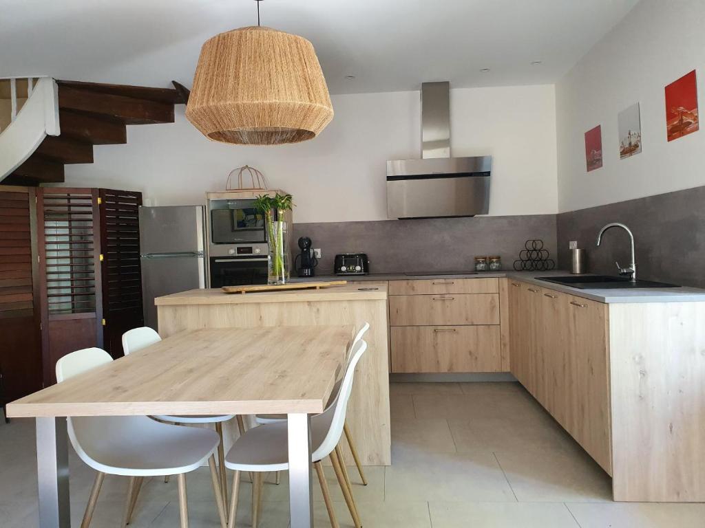 - une cuisine avec une table en bois et des chaises blanches dans l'établissement Les Pierres Lotoises - gîte les grandes pierres, à Reilhaguet
