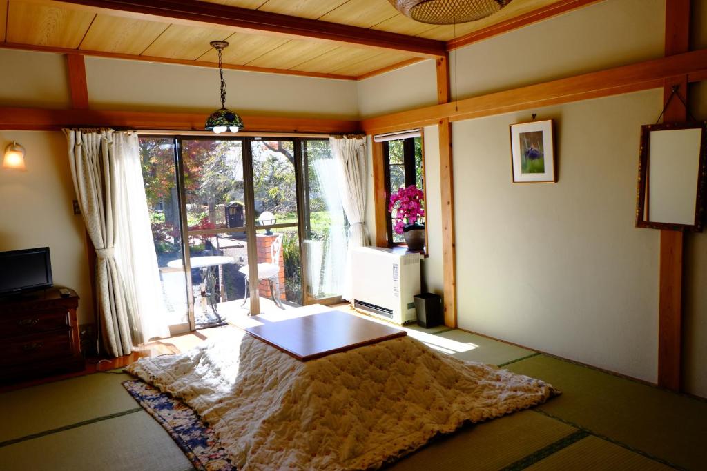 un salon avec une table et une grande fenêtre dans l'établissement Lake Oshino, à Oshino