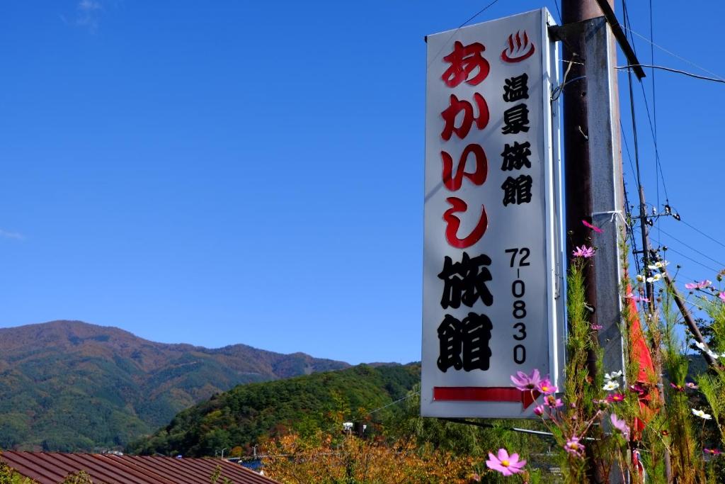 un panneau indiquant un restaurant avec des montagnes en arrière-plan dans l'établissement Akaishi Ryokan, à Fujikawaguchiko