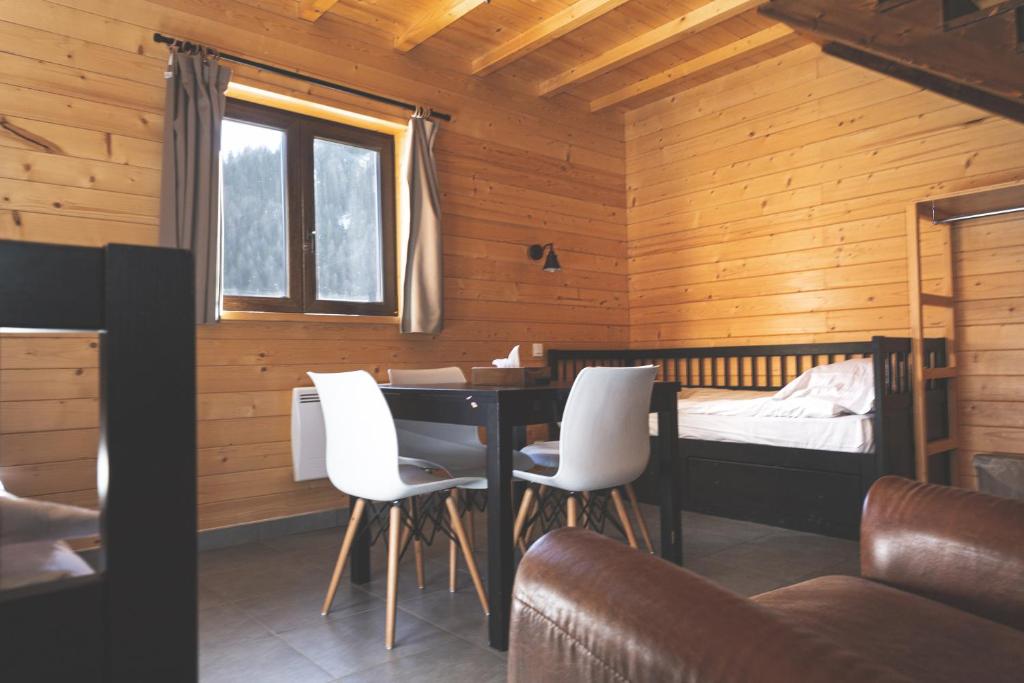 une chambre avec un lit, une table et des chaises dans l'établissement Le Loup Blanc, à Pra-Loup