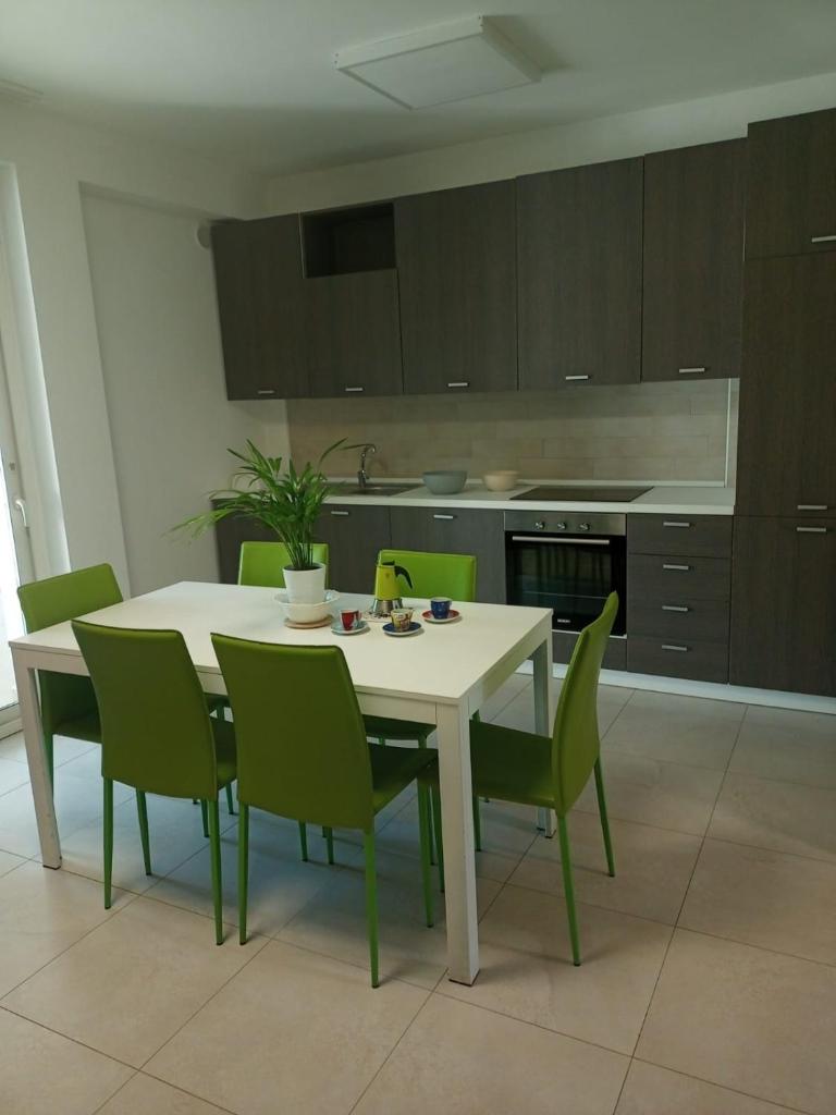 une cuisine avec une table blanche et des chaises vertes dans l'établissement I GIARDINI DI ZEUS, à Métaponte 22 autres photos