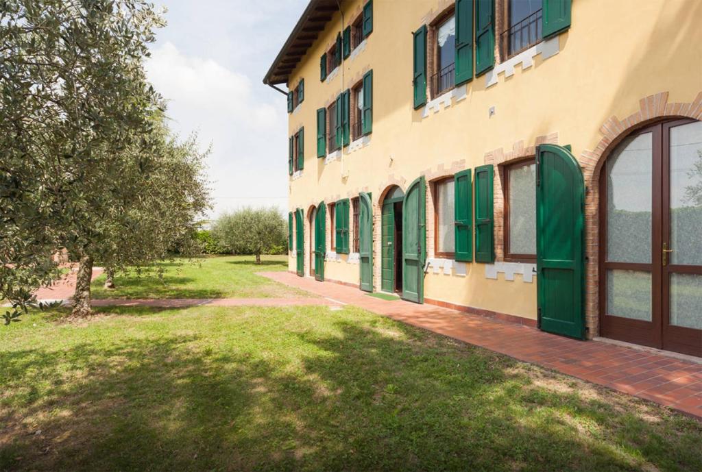 - une vue extérieure sur un bâtiment avec des portes vertes dans l'établissement TABACHERA x10 Cascina with Private Pool Sirmione GARDA LAKE, à Pozzolengo