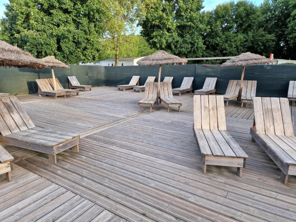 - un bouquet de chaises et de parasols sur une terrasse en bois dans l'établissement Grand Mobile home dans camping, à Mimizan