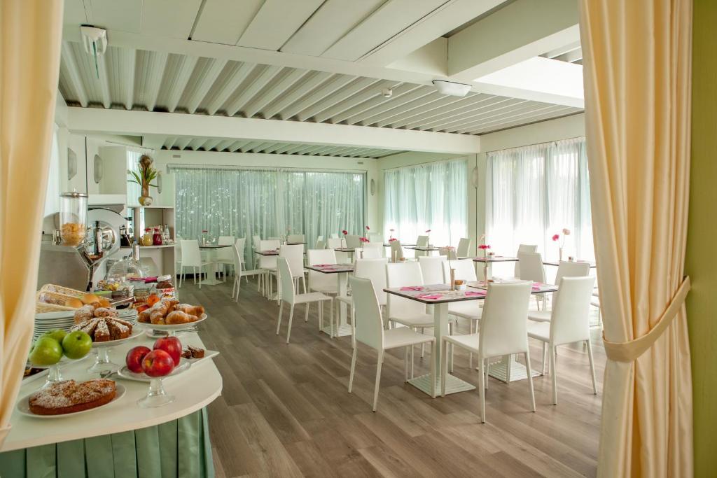 une salle à manger avec des tables et des chaises avec de la nourriture dans l'établissement Hotel Aristeo, à Rimini