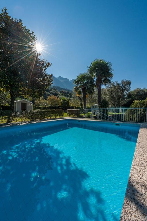 une grande piscine bleue avec le soleil en arrière-plan dans l'établissement Hotel Villa Carmen, à Malcesine