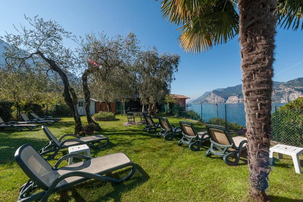 une rangée de chaises longues sur l'herbe près de l'eau dans l'établissement Hotel Villa Carmen, à Malcesine