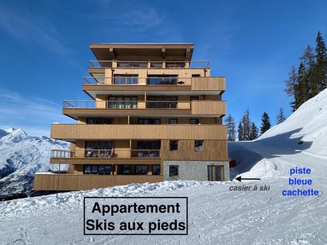un bâtiment au sommet d'une colline enneigée avec un panneau dans l'établissement LE RIDGE nouvelle résidence prestige - Les Arcs Paradiski, à Bourg-Saint-Maurice