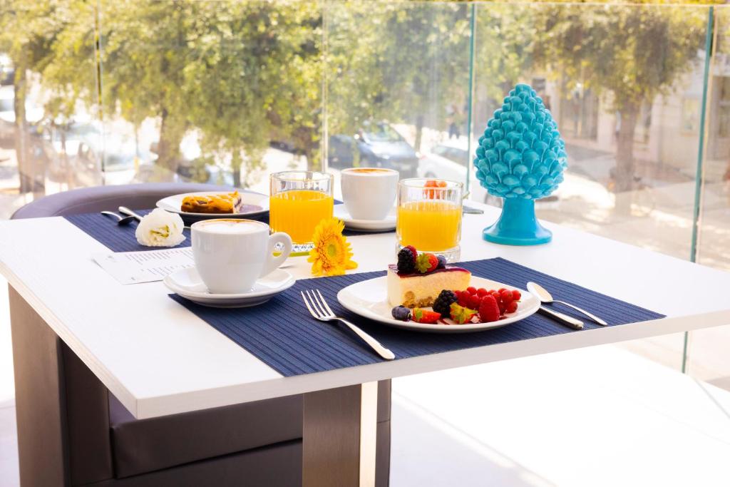une table avec un petit-déjeuner composé de gâteaux et de jus d'orange dans l'établissement POPULA - The Lifestyle Hotel, à Gallipoli