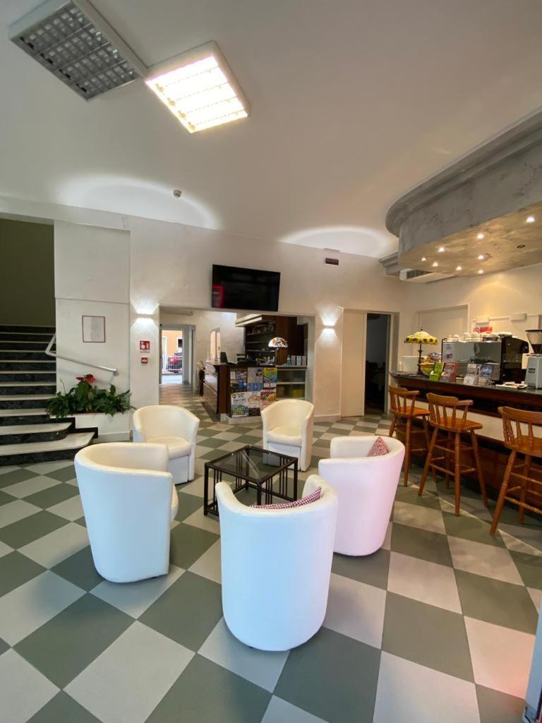 un hall avec des chaises et des tables blanches ainsi qu'un bar dans l'établissement Hotel Bahia, à Caorle 20 autres photos