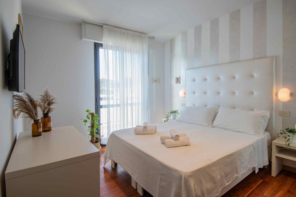 une chambre avec un grand lit blanc avec deux serviettes dessus dans l'établissement Hotel Baby B&B, à Milano Marittima