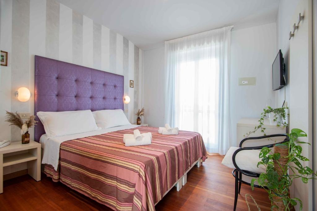 - une chambre avec un grand lit et une tête de lit violette dans l'établissement Hotel Baby B&B, à Milano Marittima