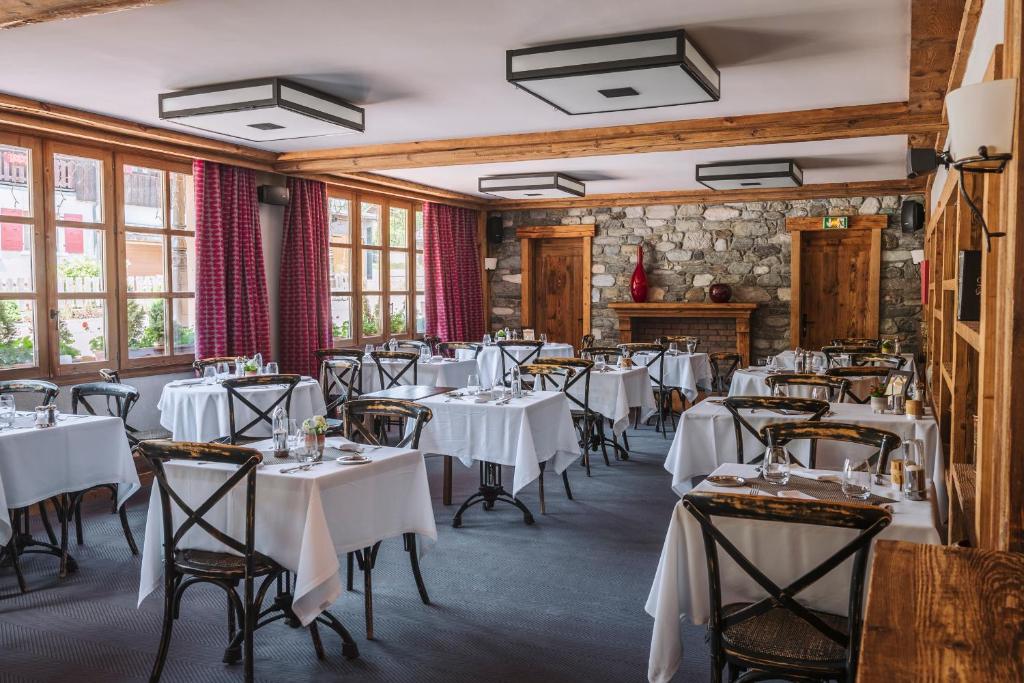 une salle à manger avec des tables et des chaises blanches dans l'établissement La Maison Hôtel Les Peupliers, à Courchevel
