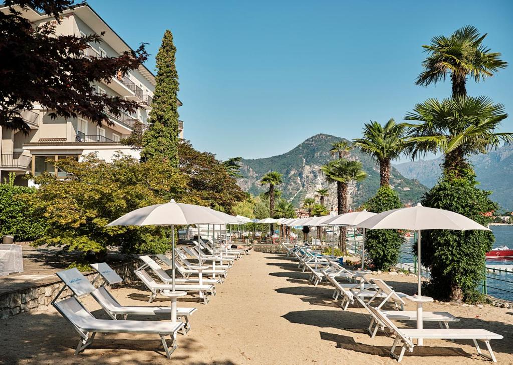une rangée de chaises longues et de parasols sur une plage dans l'établissement Hotel Carillon, à Baveno