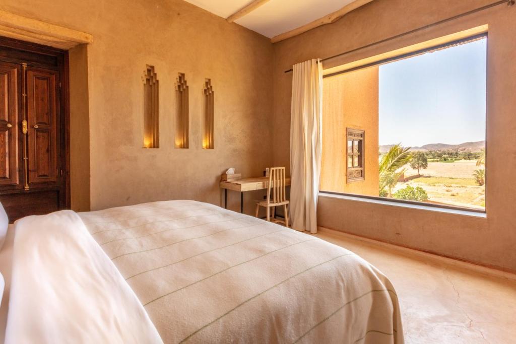 une chambre avec un lit et une grande fenêtre dans l'établissement Kasbah Tamsna, à Ouarzazate