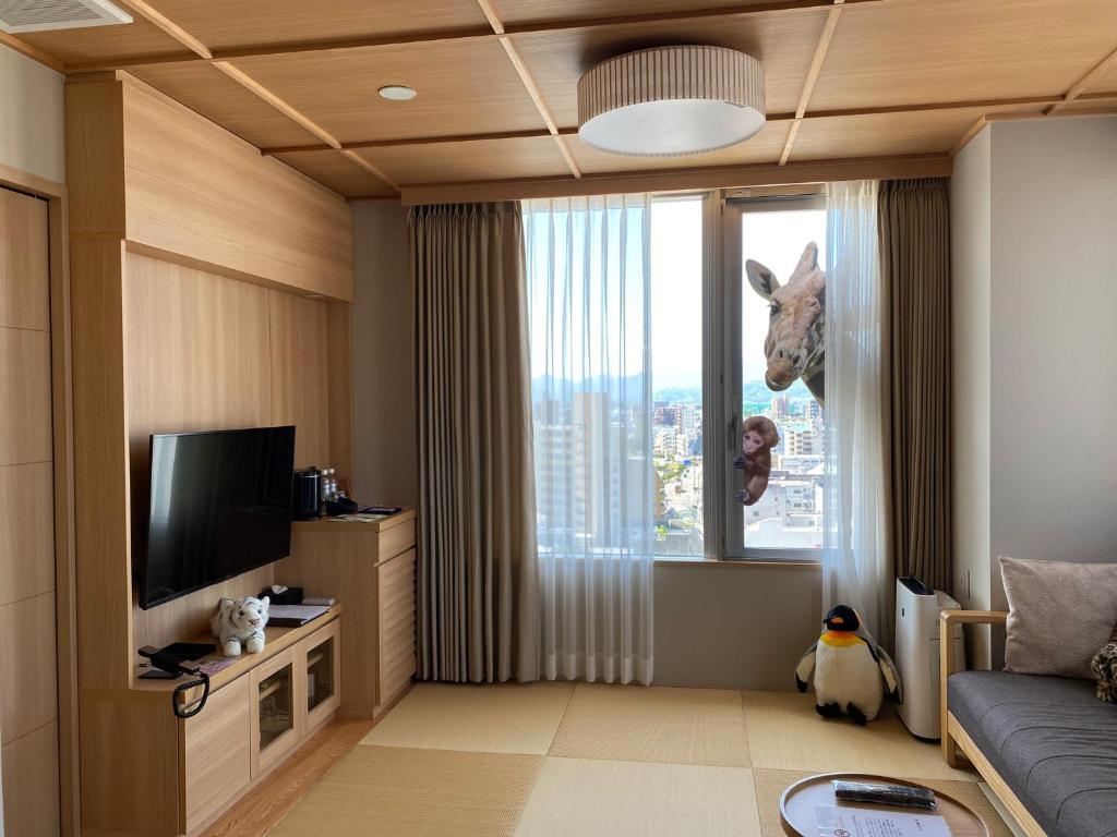 - un salon avec un canapé et une fenêtre avec une statue de girafe dans l'établissement Kowakuen Haruka, à Matsuyama