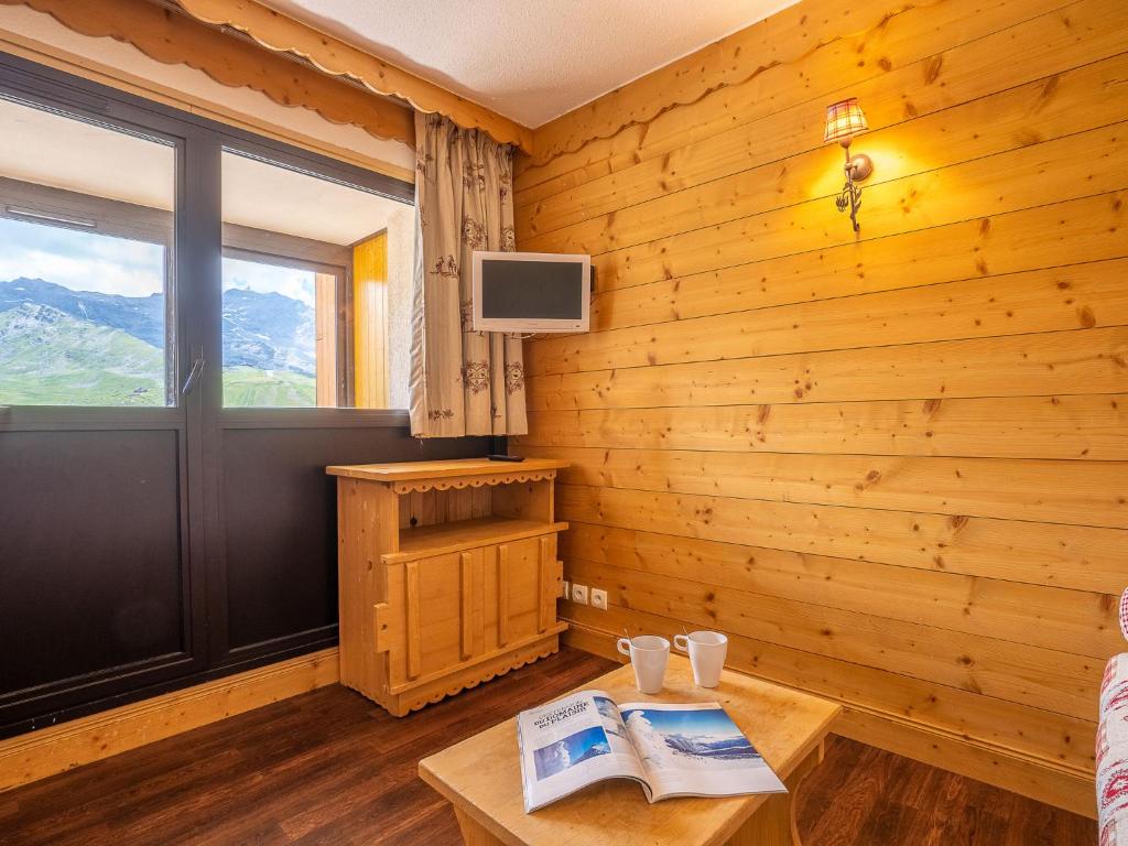Cette chambre dispose d'un mur en bois, d'une télévision et d'une table. dans l'établissement Apartment Vanoise 751 by Interhome, à Val Thorens