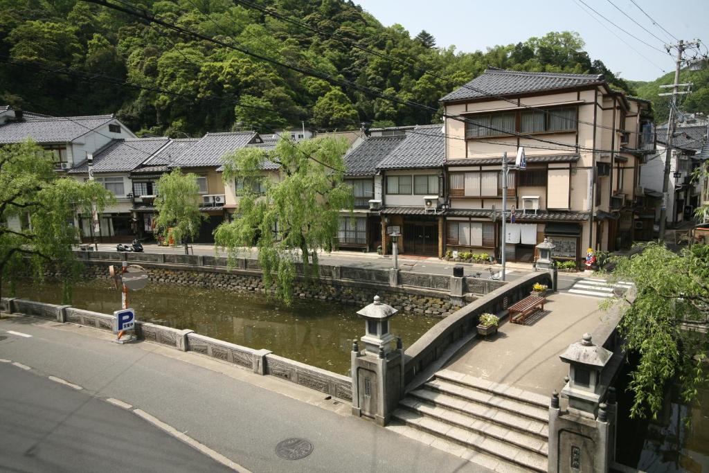 une ville avec des maisons et une rivière avec des bâtiments dans l'établissement Kinosaki Onsen Kawaguchiya Honkan, à Toyooka