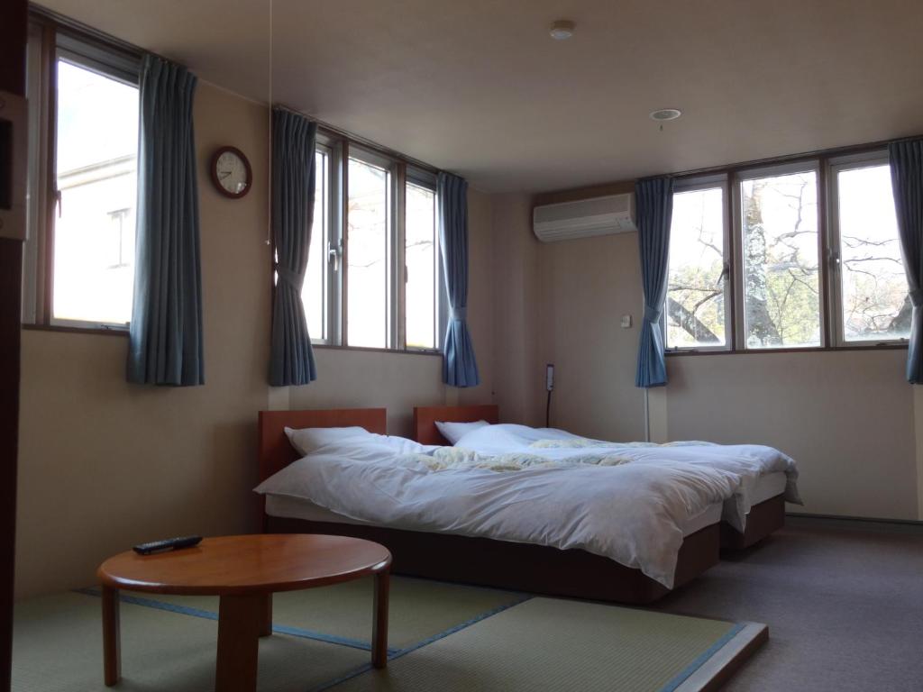une chambre avec un lit, une table et des fenêtres dans l'établissement Oomukou Ryokan, à Hakuba