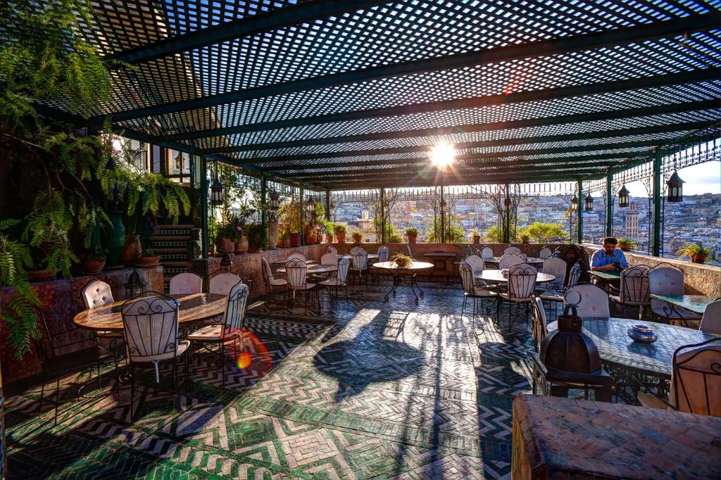 un restaurant avec des tables et des chaises et une vue sur la ville dans l'établissement Dar Tazi - Medina View, à Fès
