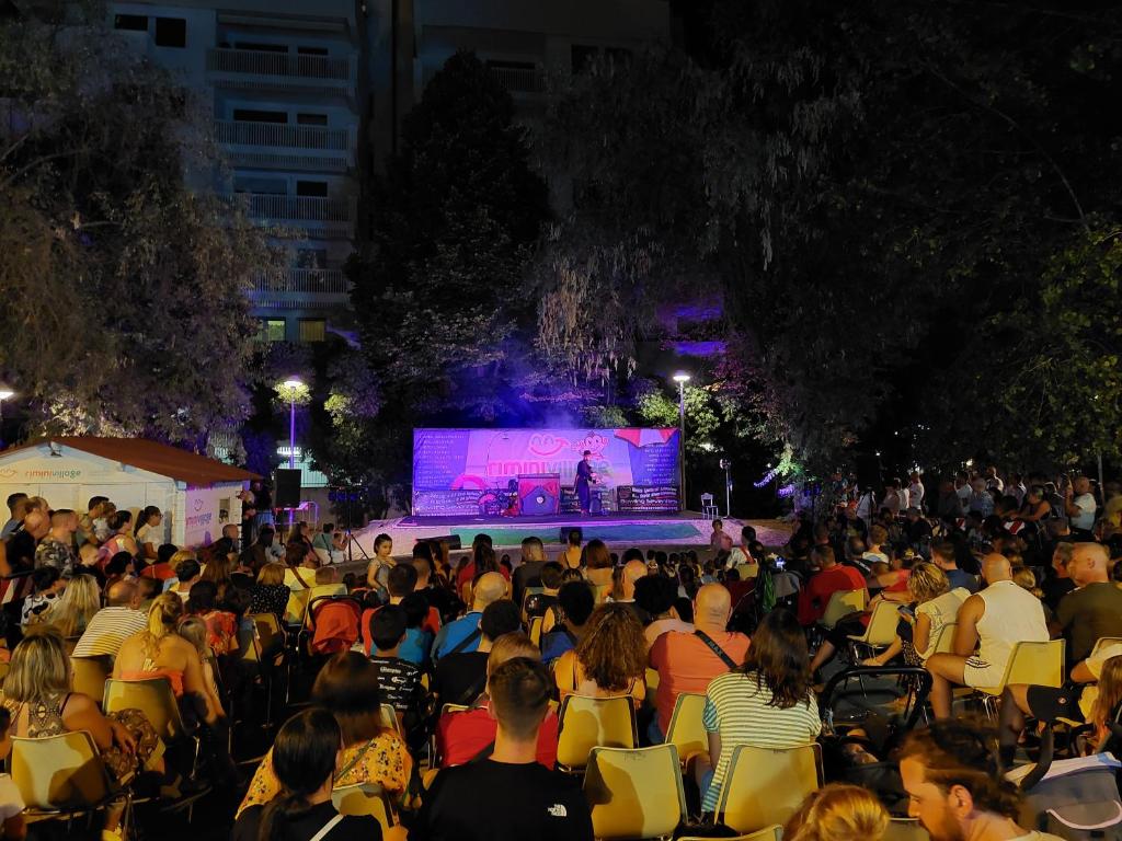 une foule de personnes assises sur des chaises regardant une scène dans l'établissement Hotel Caravel Park, à Rimini
