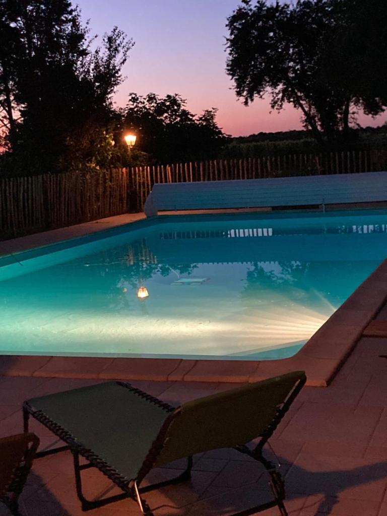 - une piscine avec une table et des chaises la nuit dans l'établissement Gites le Mathelin, à Lamothe-Montravel