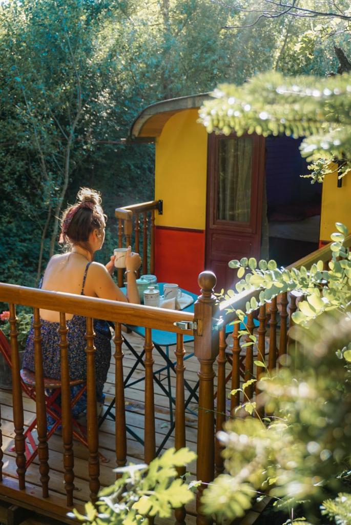 une femme assise à une table sur un pont dans l'établissement Roulotte Tzigane au bord du ruisseau - Drôme Provençale (2p), à Marsanne 5 autres photos