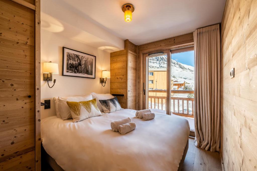 - une chambre avec un grand lit dans une pièce dotée d'une fenêtre dans l'établissement Apartment Sipo Alpe D'Huez - by EMERALD STAY, à L'Alpe-d'Huez