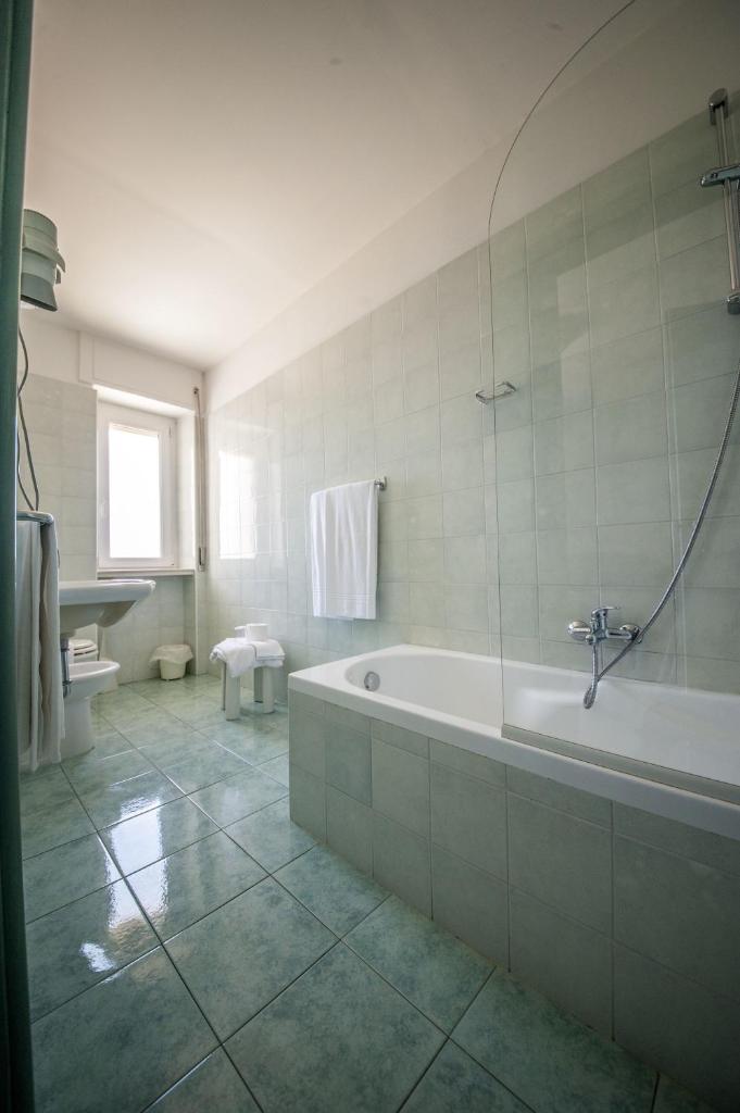 une grande salle de bain avec baignoire et douche dans l'établissement Hotel Murano, à Rossano