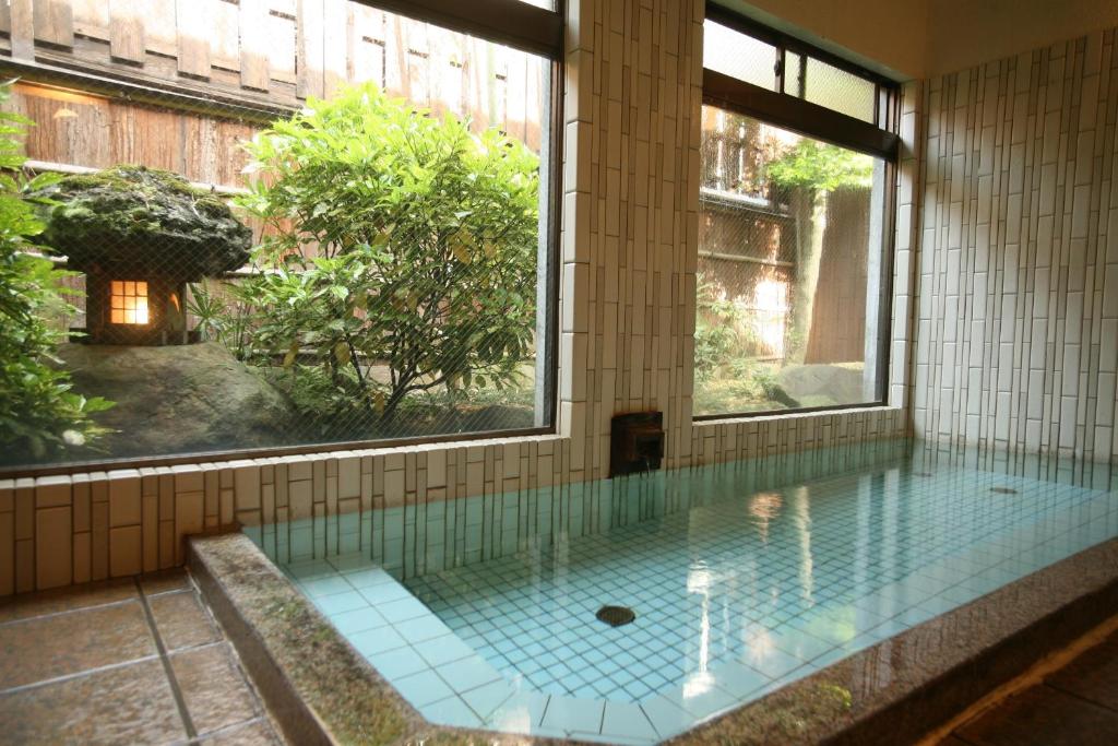 une piscine dans un immeuble avec une grande fenêtre dans l'établissement Kinosaki Onsen Kawaguchiya Honkan, à Toyooka