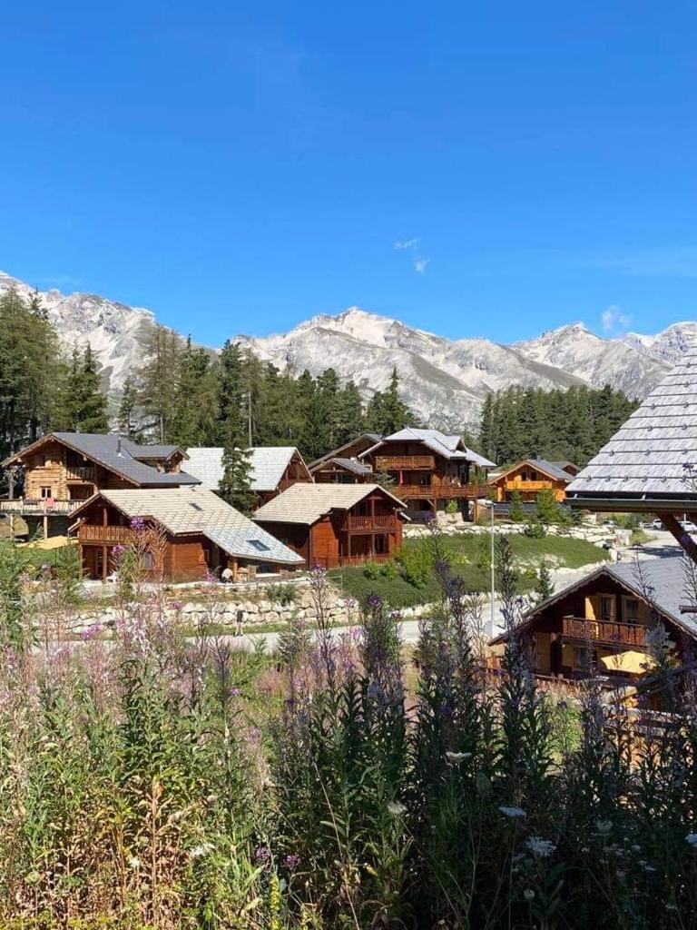 un groupe de maisons avec des montagnes en arrière-plan dans l'établissement Chalet le Lagopède, à La Joue du Loup