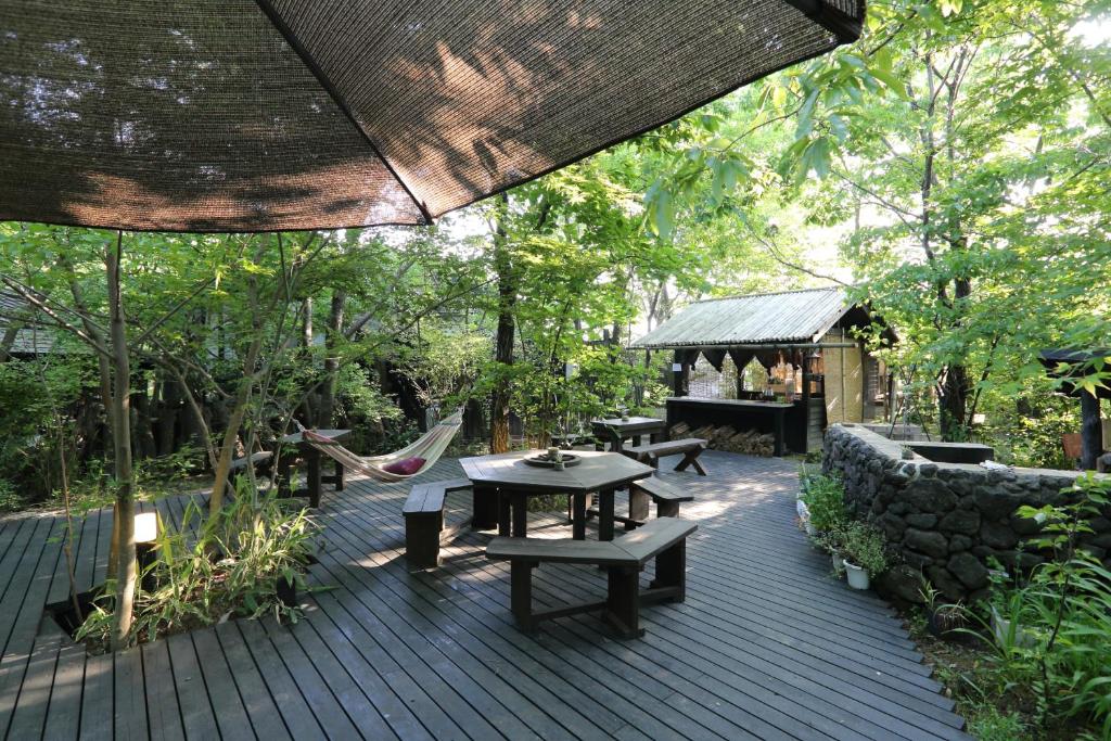 une terrasse en bois avec des tables et des chaises ainsi qu'un pavillon dans l'établissement Shinwaen, à Aso