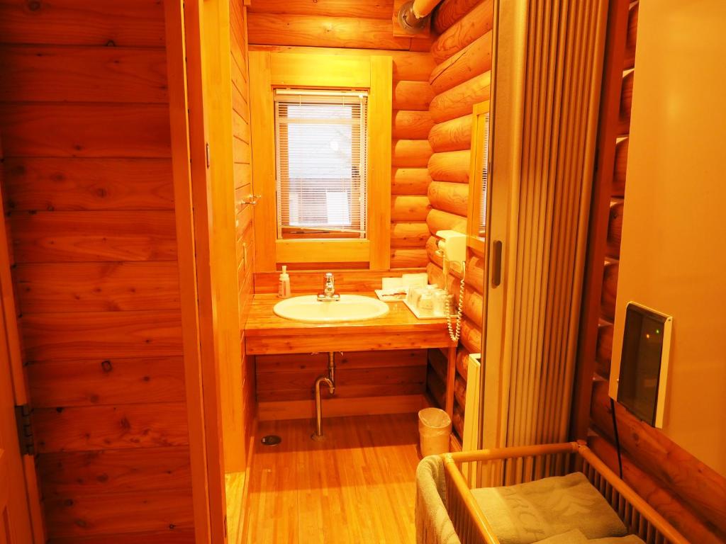 une salle de bain avec un lavabo dans une cabane en rondins dans l'établissement Log Hotel Larch Lake Kanayama, à Minamifurano
