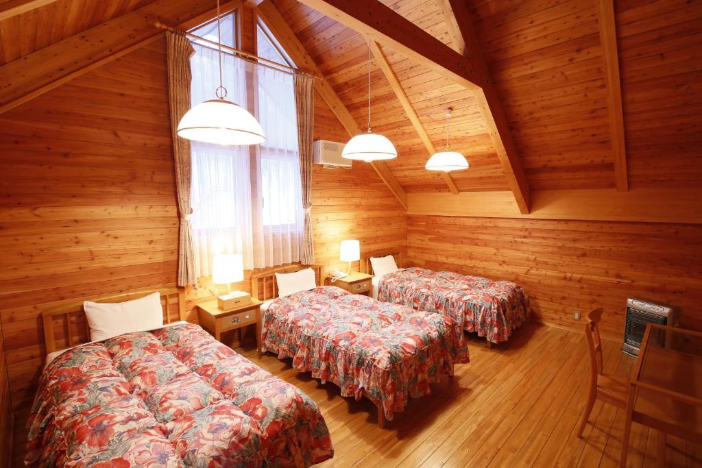 deux lits dans une chambre aux murs en bois dans l'établissement Log Hotel Larch Lake Kanayama, à Minamifurano 37 autres photos