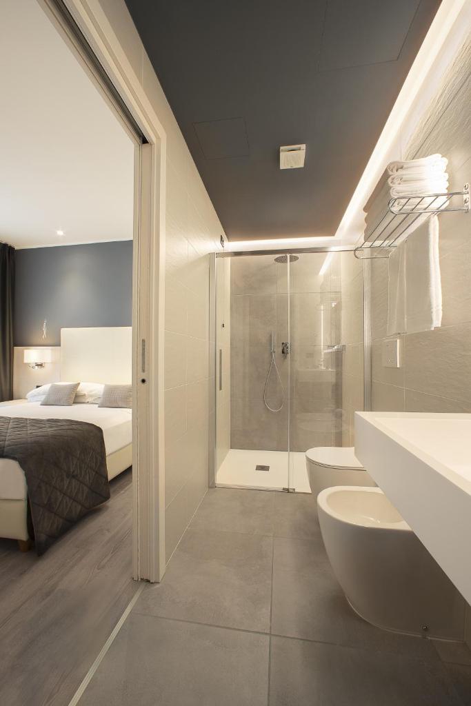 une salle de bain avec une douche, un lit et un lavabo dans l'établissement Hotel Sayonara, à Lido di Jesolo