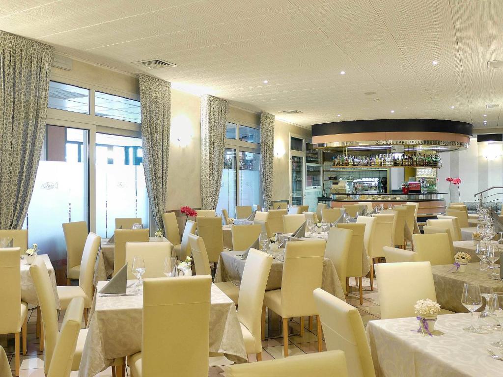une salle à manger avec des tables et des chaises blanches dans l'établissement Hotel Storione, à Lido di Jesolo