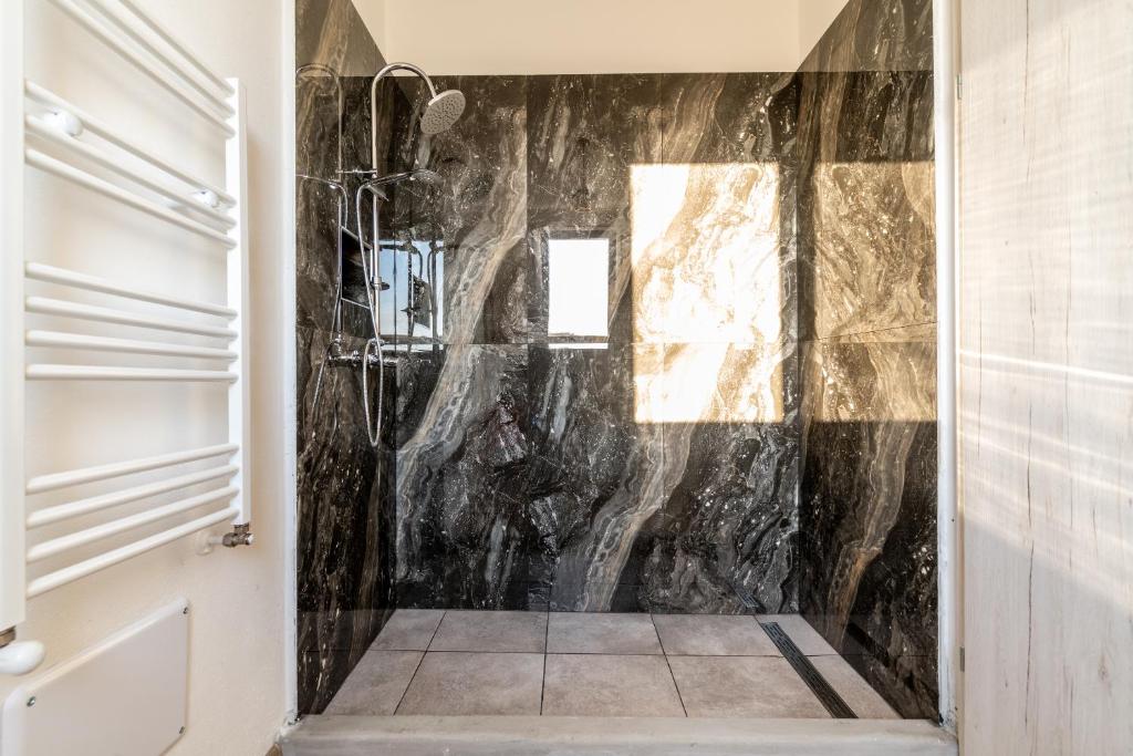La salle de bains est pourvue d'un mur en marbre noir. dans l'établissement Ostuni Hills Boutique Villa-AC in every room, à Ostuni