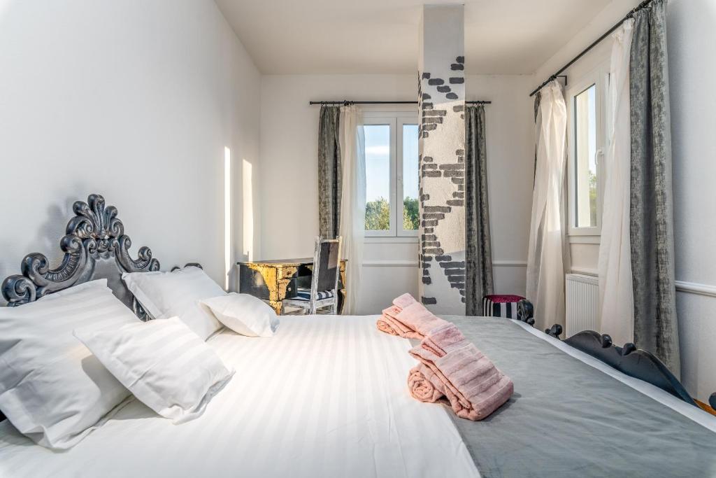 une chambre avec un grand lit blanc avec deux serviettes dessus dans l'établissement Ostuni Hills Boutique Villa-AC in every room, à Ostuni