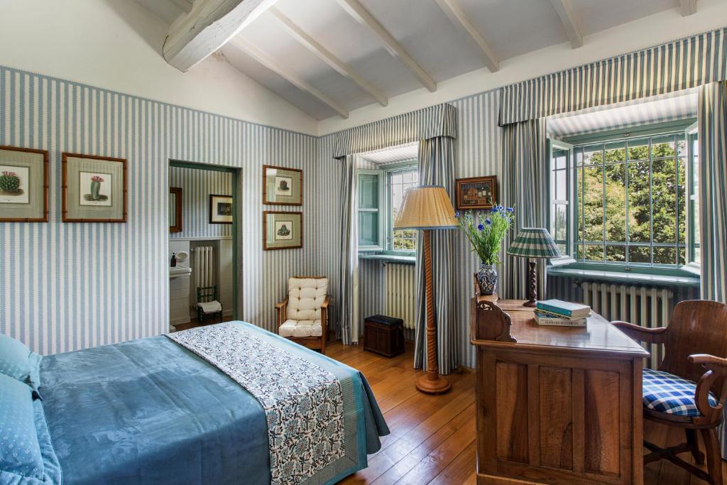 - une chambre avec un lit bleu, un bureau et des fenêtres dans l'établissement Villa Colonica Tuori at Tenuta Schifanoia, à San Piero a Sieve