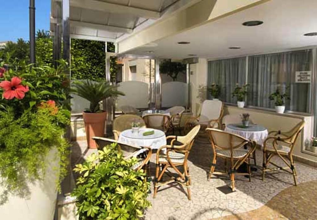 d'une terrasse avec des tables, des chaises et des plantes. dans l'établissement Hotel Acerboli, à Rimini