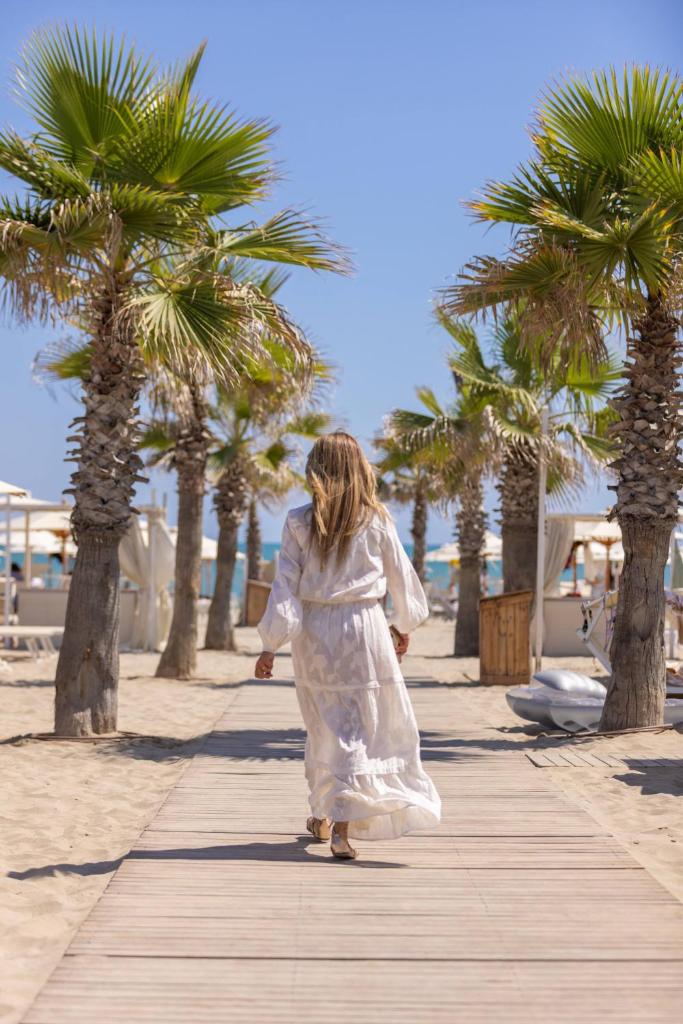 une femme en robe blanche marchant sur le trottoir dans l'établissement Hotel Lungomare, à Riccione