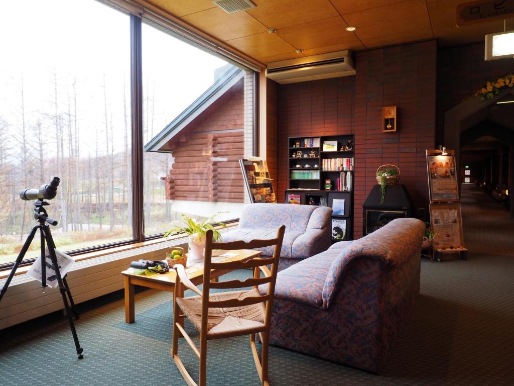 - un salon avec un canapé, une chaise et une caméra dans l'établissement Log Hotel Larch Lake Kanayama, à Minamifurano
