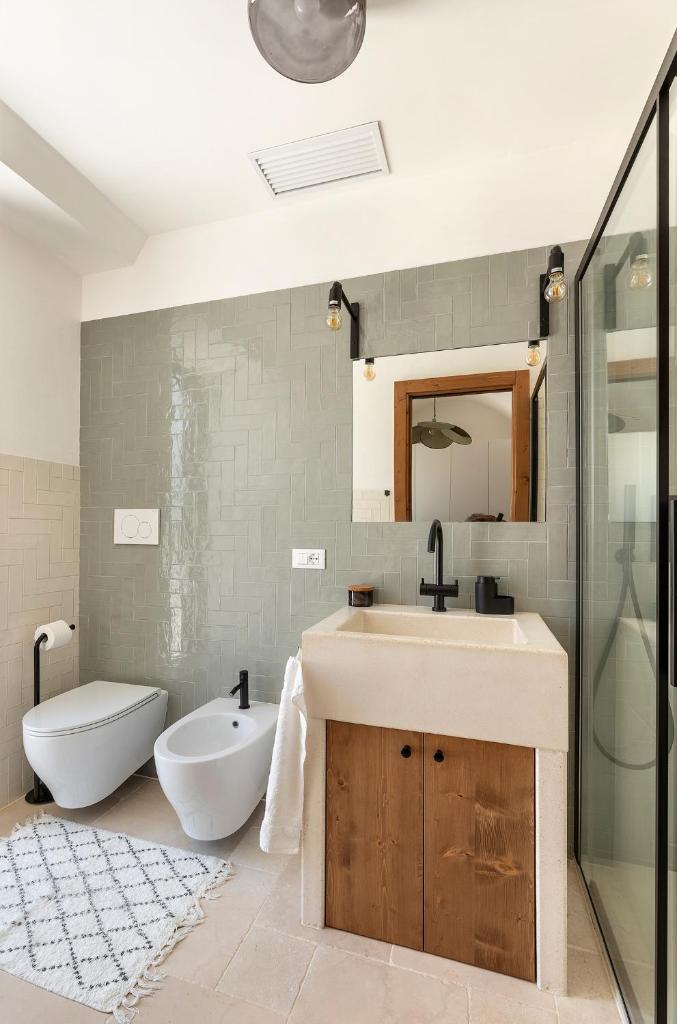 une salle de bain avec un lavabo, des toilettes et un miroir dans l'établissement Vilaa Isa Beautiful Villa and trullo in Ostuni, à Ostuni